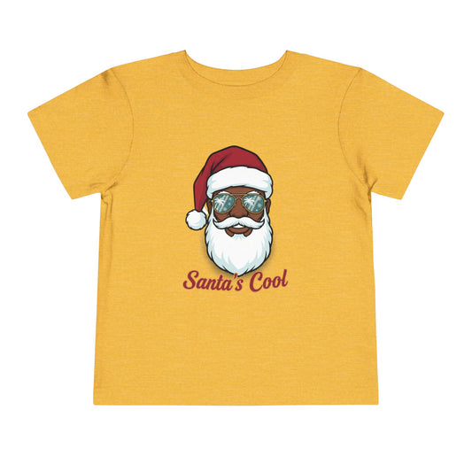 Child wearing a white t-shirt with a graphic of a person in a Santa hat and sunglasses, with text 'Santa's Cool', on a white background.