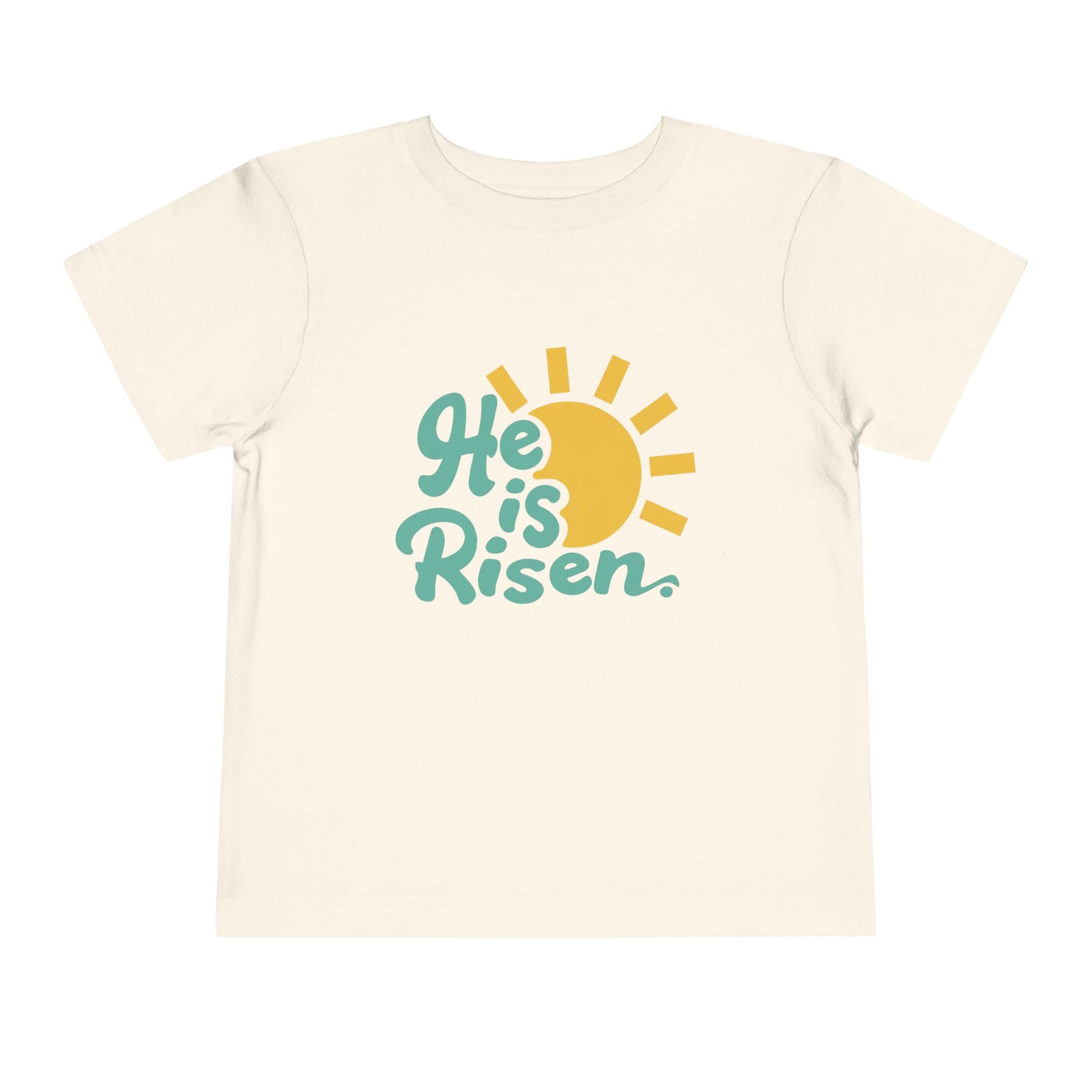 Beige t-shirt with 'He is Risen' text and sun graphic on a white background