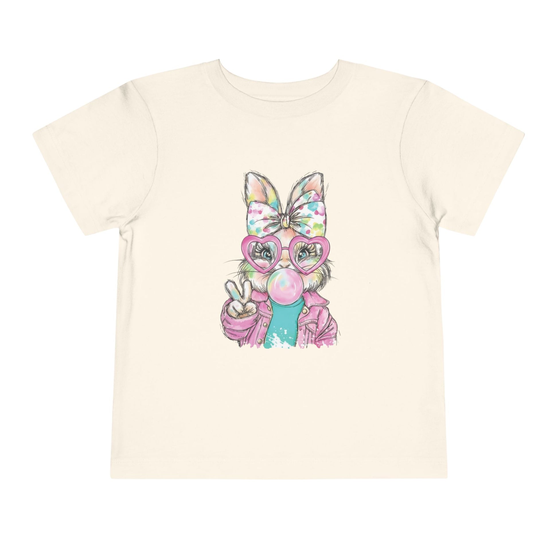 Beige t-shirt with a colorful cartoon bunny holding a peace sign on a white background