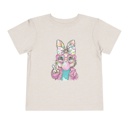 Beige t-shirt with a colorful graphic of a cat wearing glasses and a bow on a white background