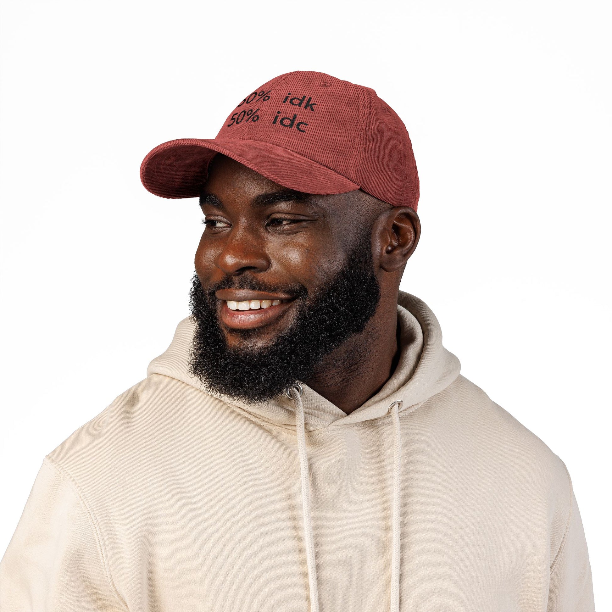Man wearing a red cap with a logo and a beige hoodie on a white background