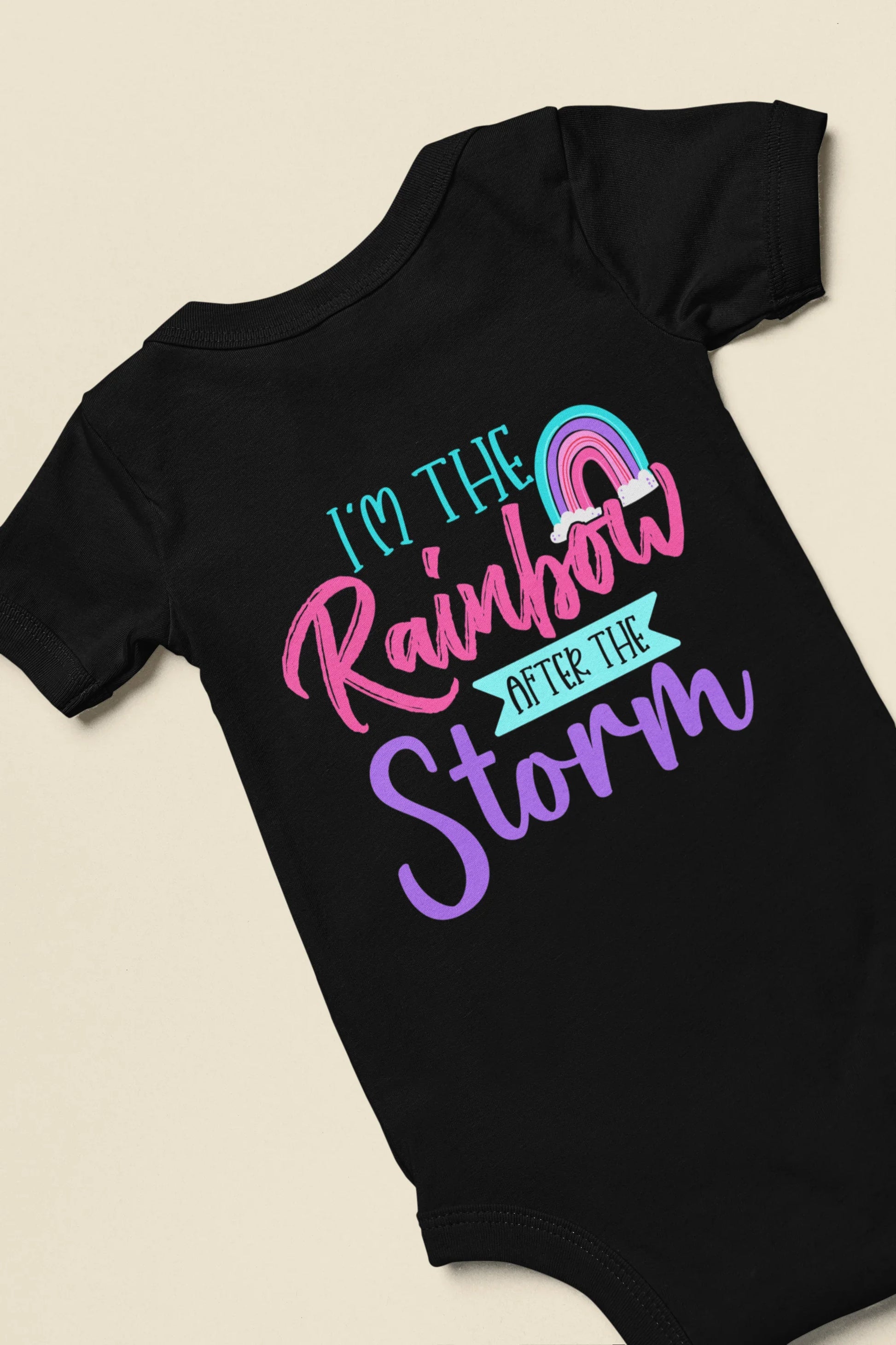 Black baby onesie with colorful text design on a beige background