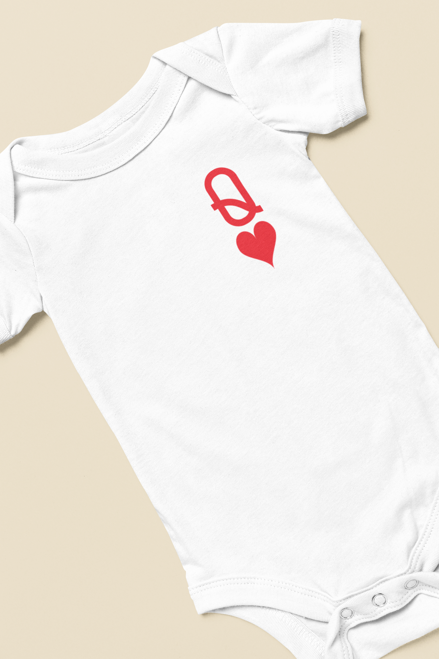 White baby onesie with a red clasp and heart design on a beige background