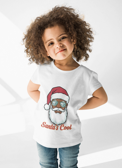 Child wearing a white t-shirt with a graphic of a person in a Santa hat and sunglasses, with text 'Santa's Cool', on a white background.