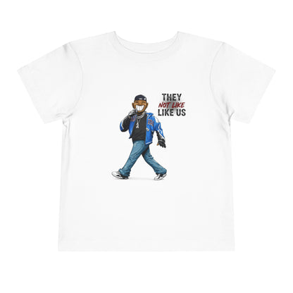 White t-shirt with a graphic of a person wearing a mask and text 'They Not Like Us' on a white background