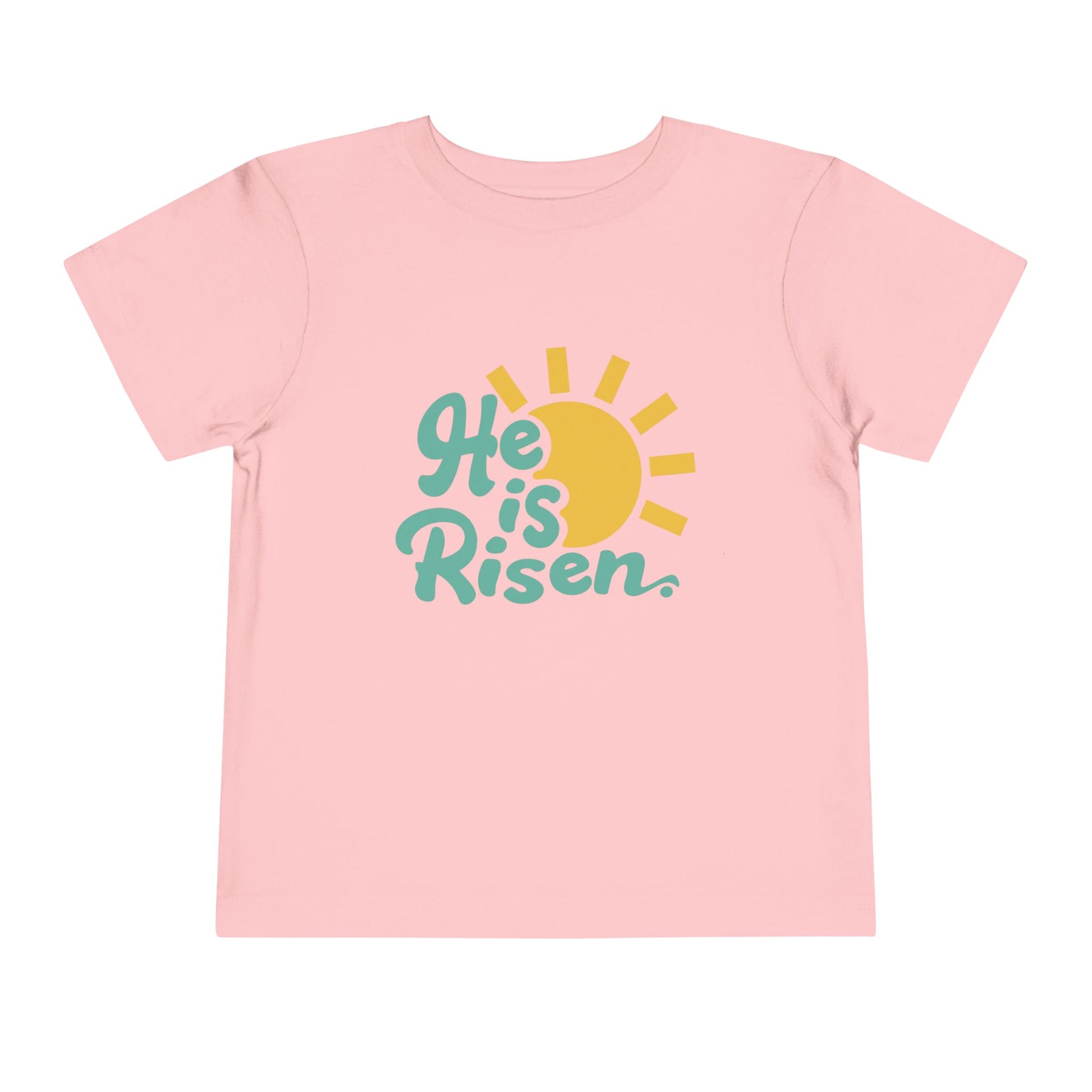 Pink t-shirt with 'He is Risen' text and sun graphic on a white background