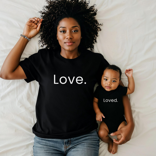 Woman and child wearing black shirts with 'Love.' and 'Loved.' text on a white background